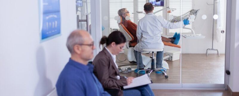 Dentiste et patient âgé analysant des dents sur une radiographie dans un bureau de consultation, assis sur une chaise. Hôpitaux de Otorrinolaringologie à Paris