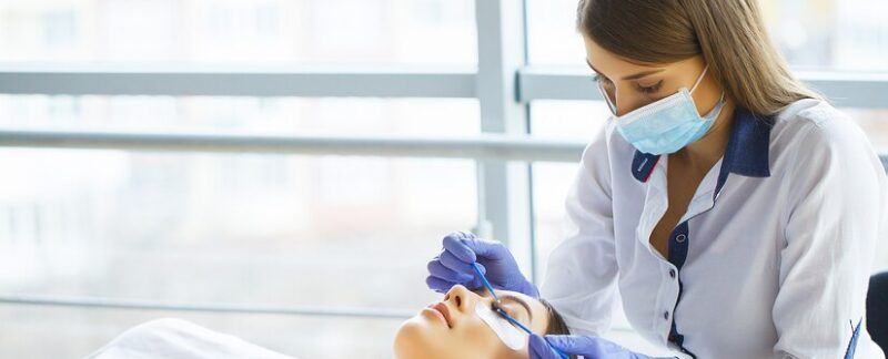 Jeune femme dégustant un verre de jus d'orange le matin alors qu'elle se détend assise sur son lit dans le cadre d'un régime alimentaire sain. meilleurs dermatologues à Paris