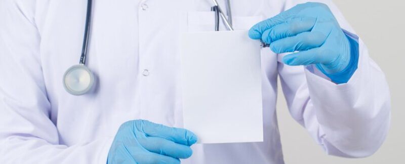 Médecin tenant une carte vierge en blouse blanche et gants. meilleurs urologues à Paris
